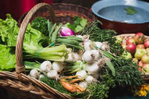 Fresh vegetables and herbs in rustic basket at Sunday market