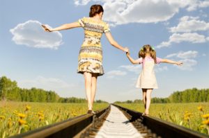 Mother and daughter balancing on train tracks