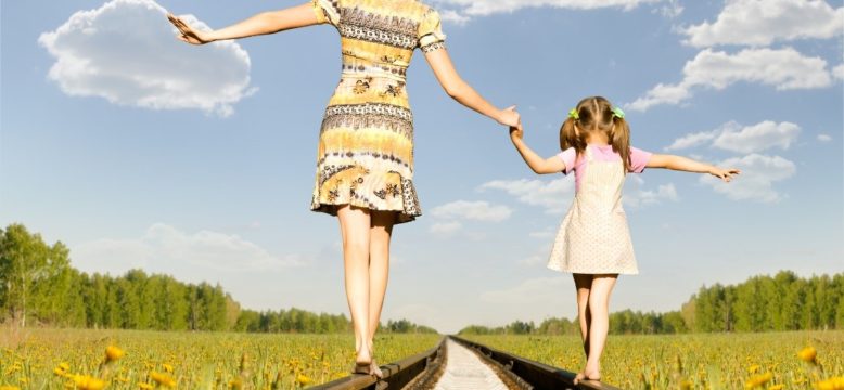 Mother and daughter balancing on train tracks