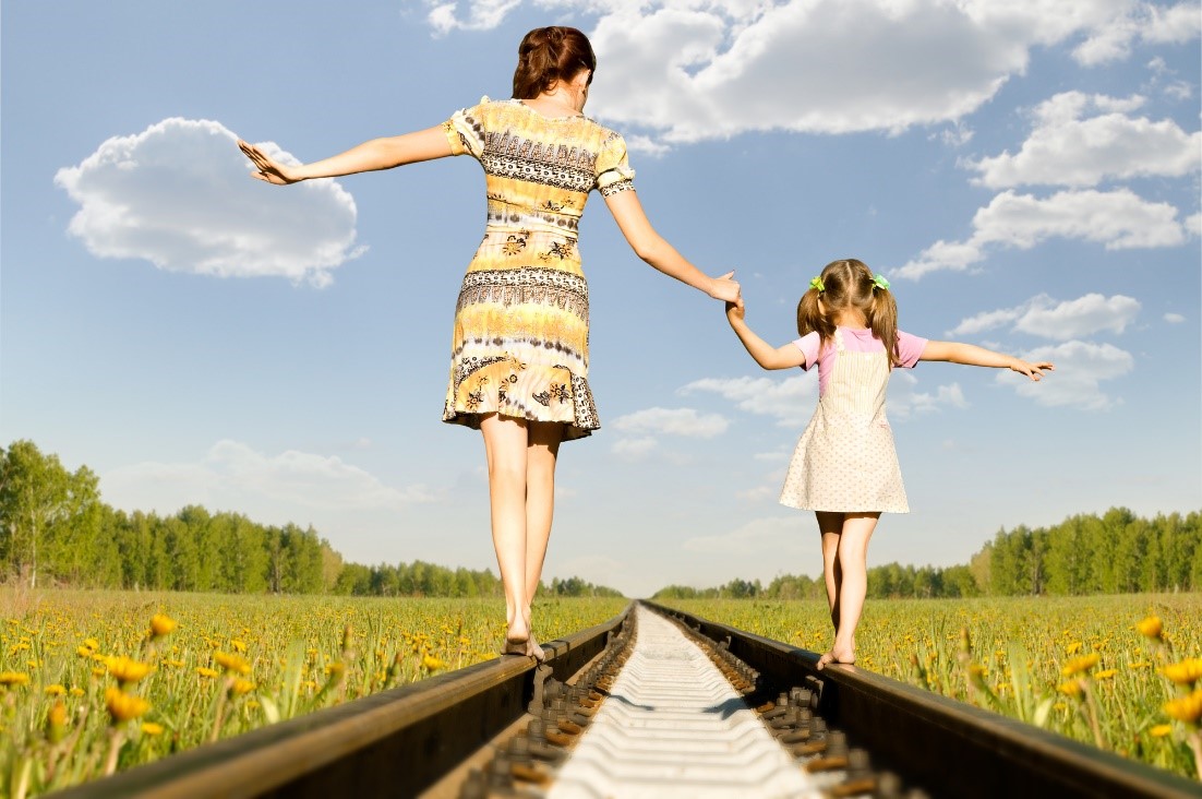 Mother and daughter balancing on train tracks.