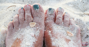 Feet covered in sand on the beach