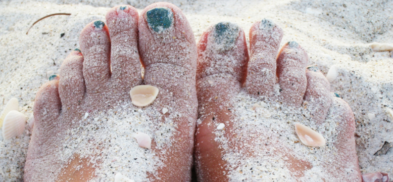 Feet covered in sand on the beach